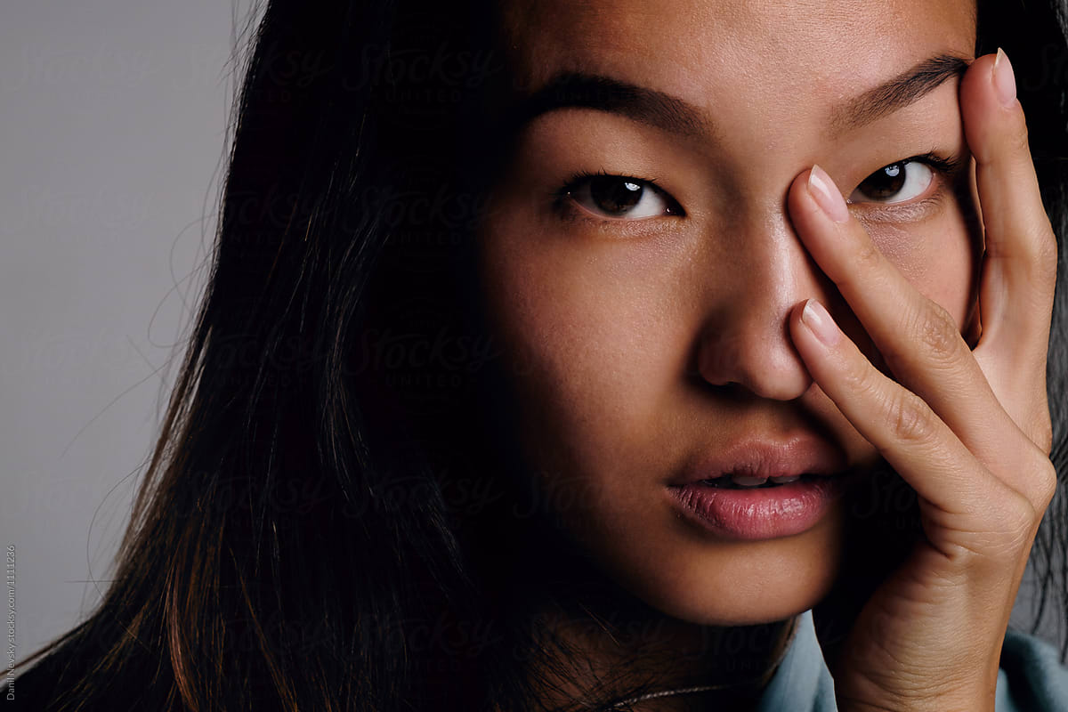 Asian girl with fingers on face looking at camera