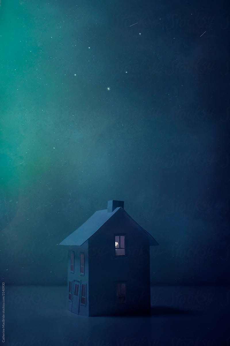 A little paper house sits under a night sky filled with stars and meteors