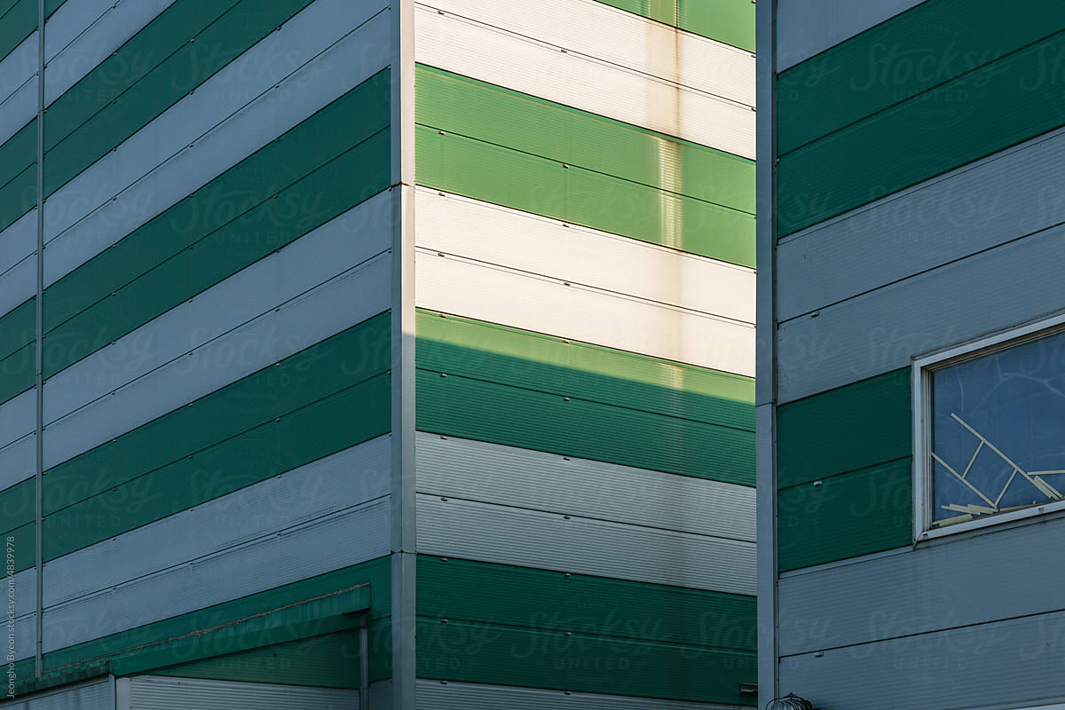 Close-up of sunlight on the green striped factory wall.