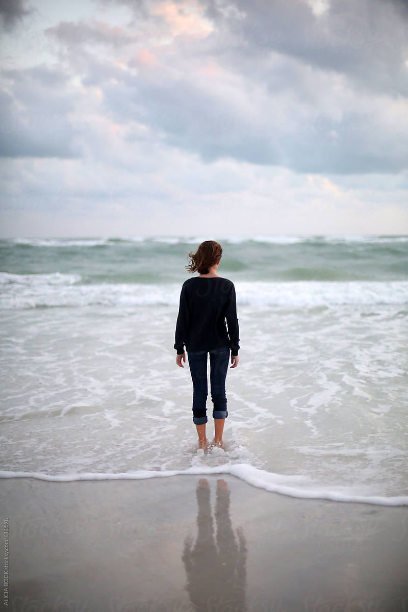 A Girl Looking Out Towards Large Waves In The Ocean