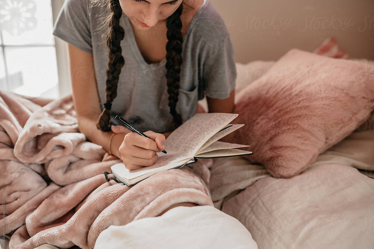 young woman journaling in her bedroom