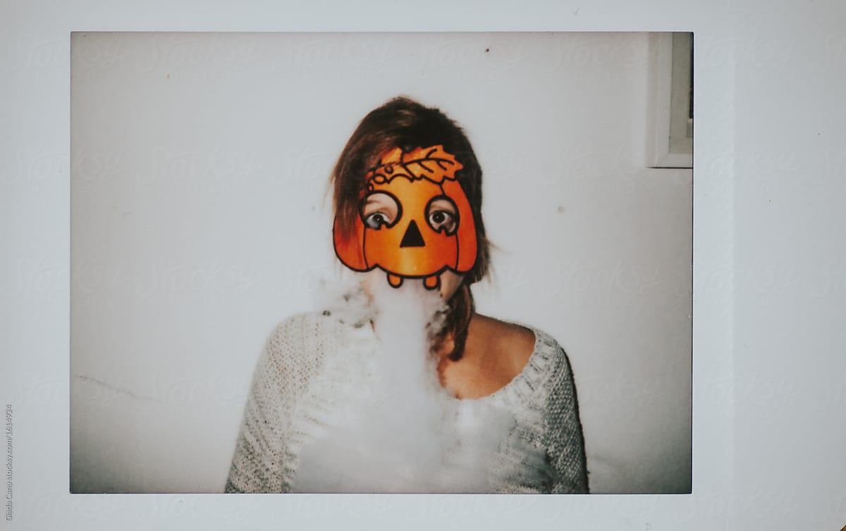 Woman with a pumpkin mask smoking an electronic cigarette