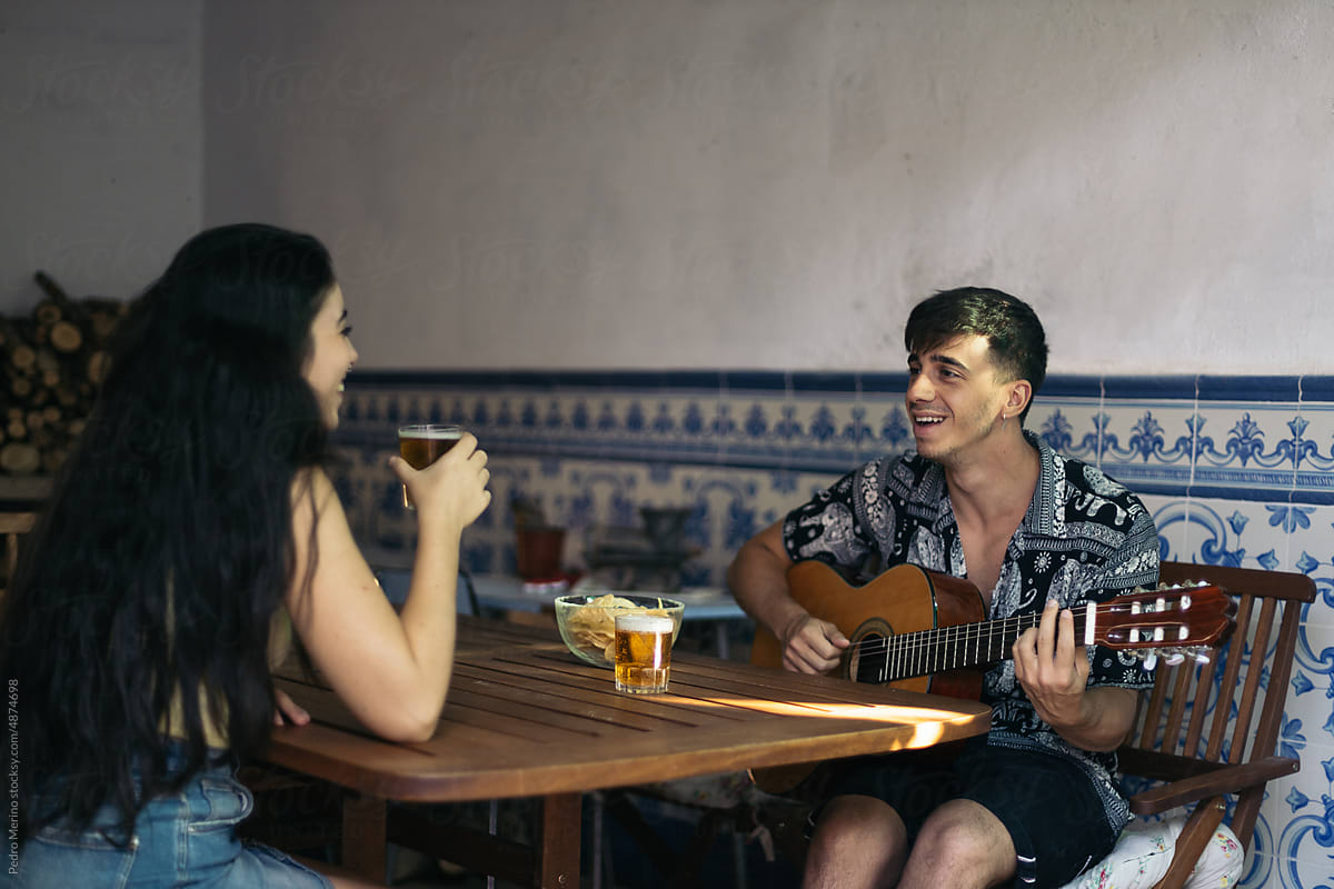 Friends drinking beer and playing Spanish guitar on a patio