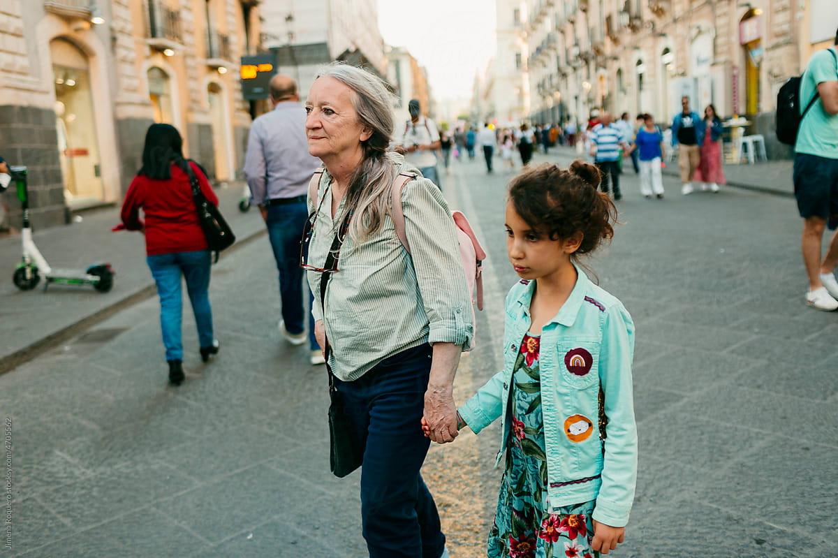 Grandmother and granddaughter walking on crowded street