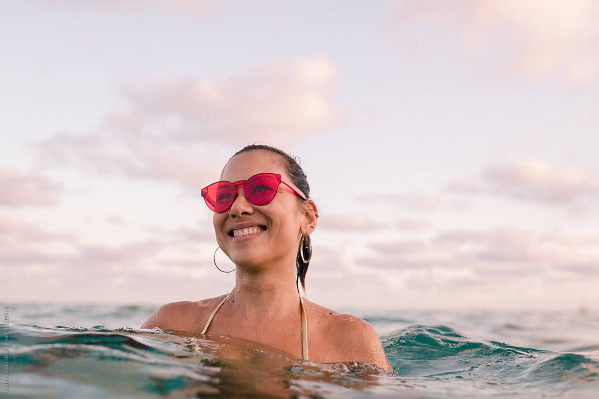Happy woman standing in the sea with red sunglasses