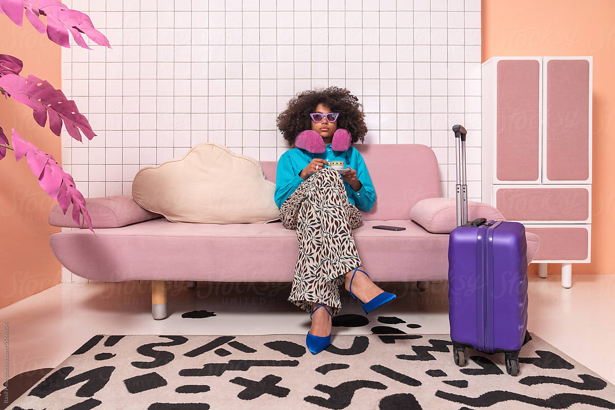 Chic Traveler with Purple Suitcase and Pink Sofa