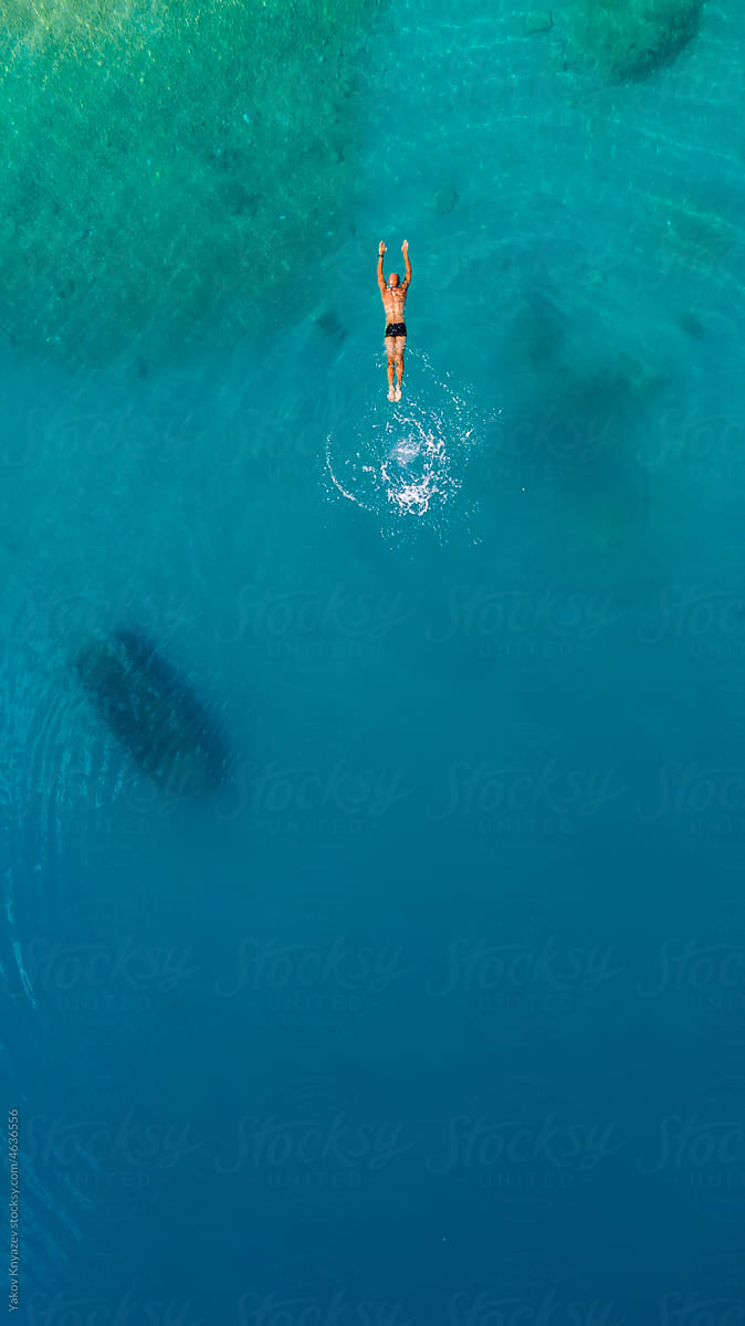 young athletic man swimming in turquoise water