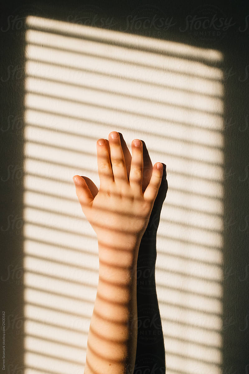 Child\'s hand playing with sunlight on a white wall