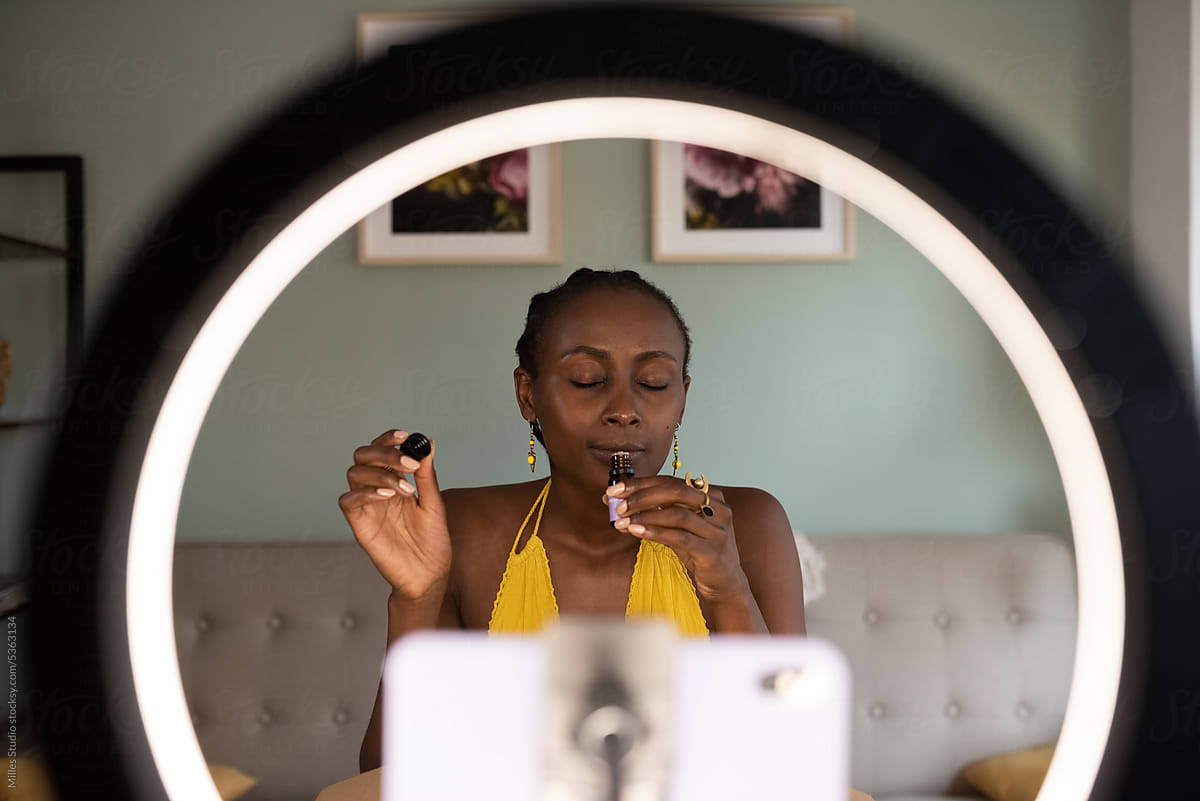 Black female blogger smelling aromatic oil in room
