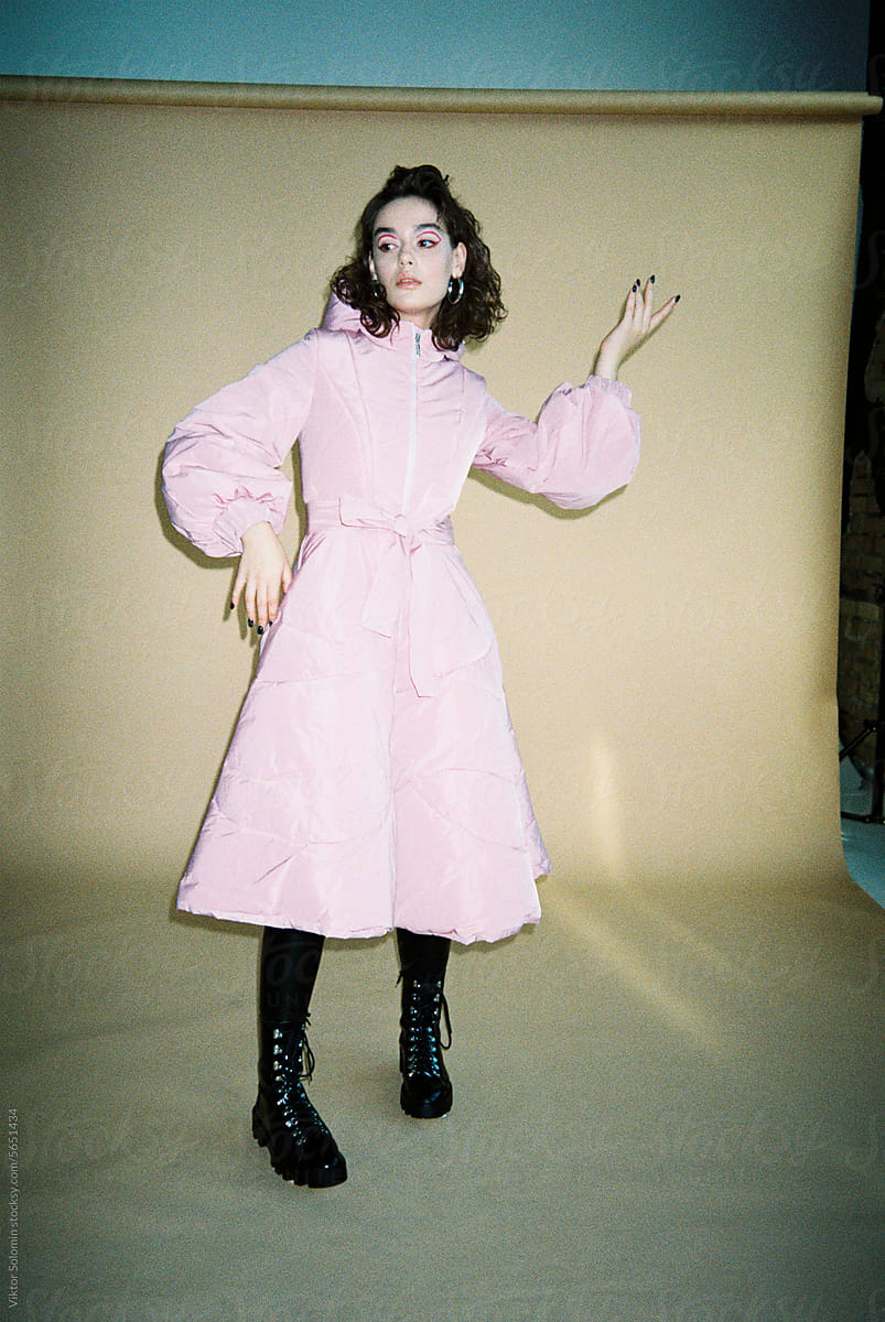 Fashion looking woman in winter pink coat posing in studio. Film photo