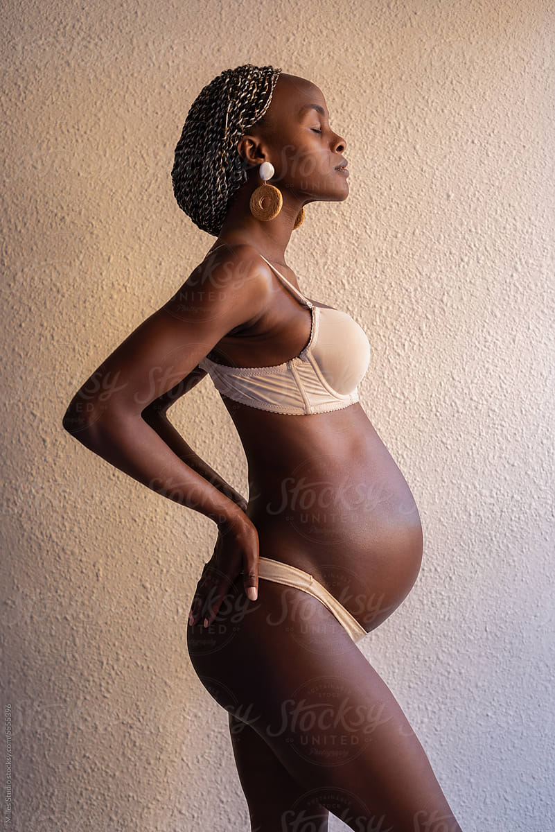 Black future mother in lingerie taking deep breath
