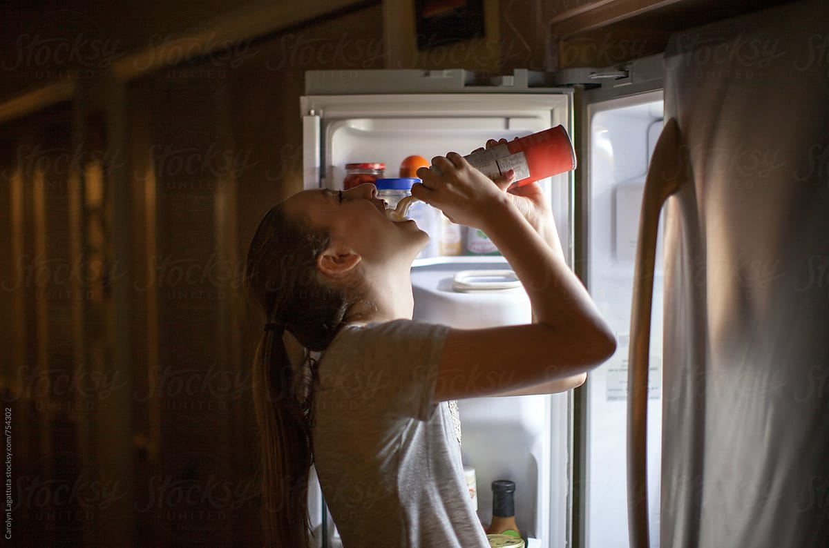 Teenage Girl Standing At The Refrigerator Spraying Whip Cream Into Her Mouth By Stocksy