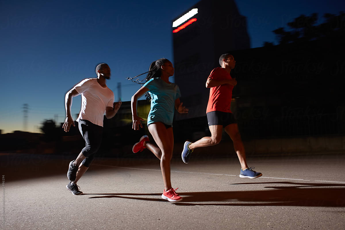 Group of black athletes running at night in urban area
