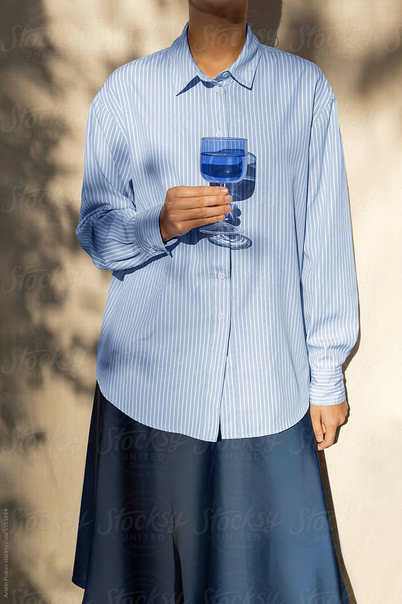 A woman holds a blue glass in her hand
