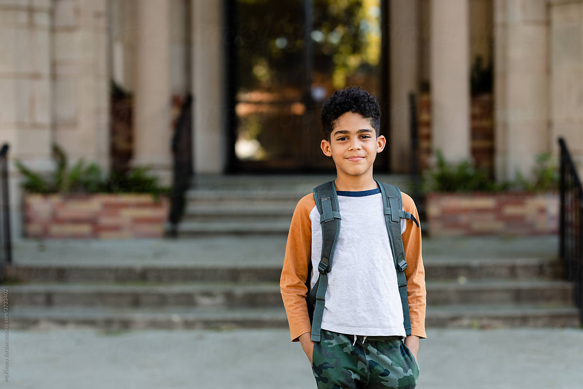 Boy Wearing a Backpack Stands in Front of an Old Building