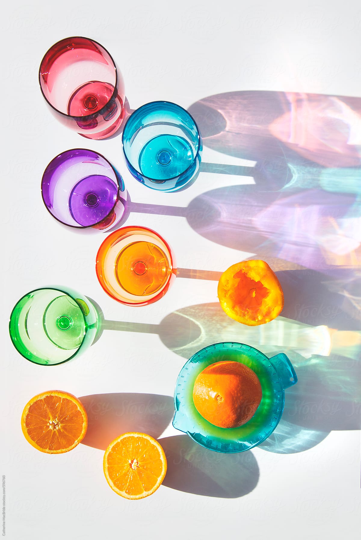 Orange fruit juice and colourful glasses and shadows