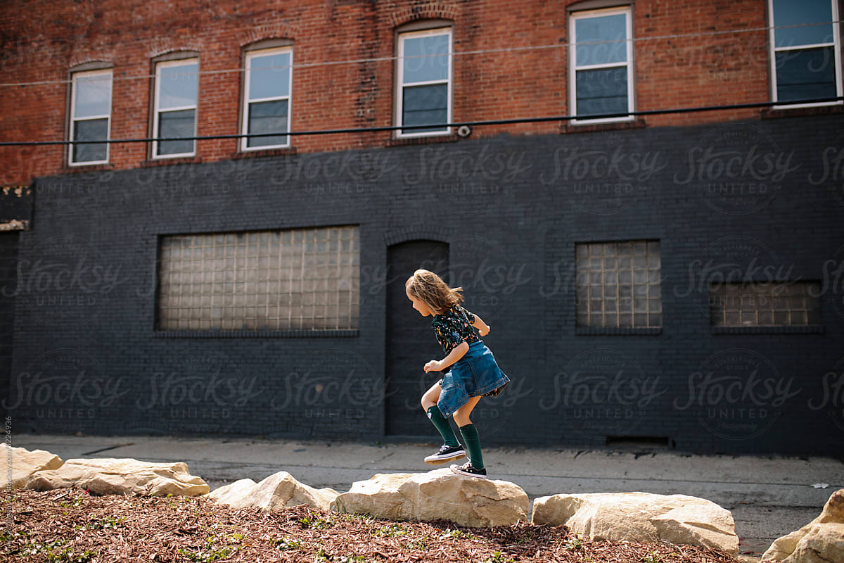 Young girl walking across rocks.