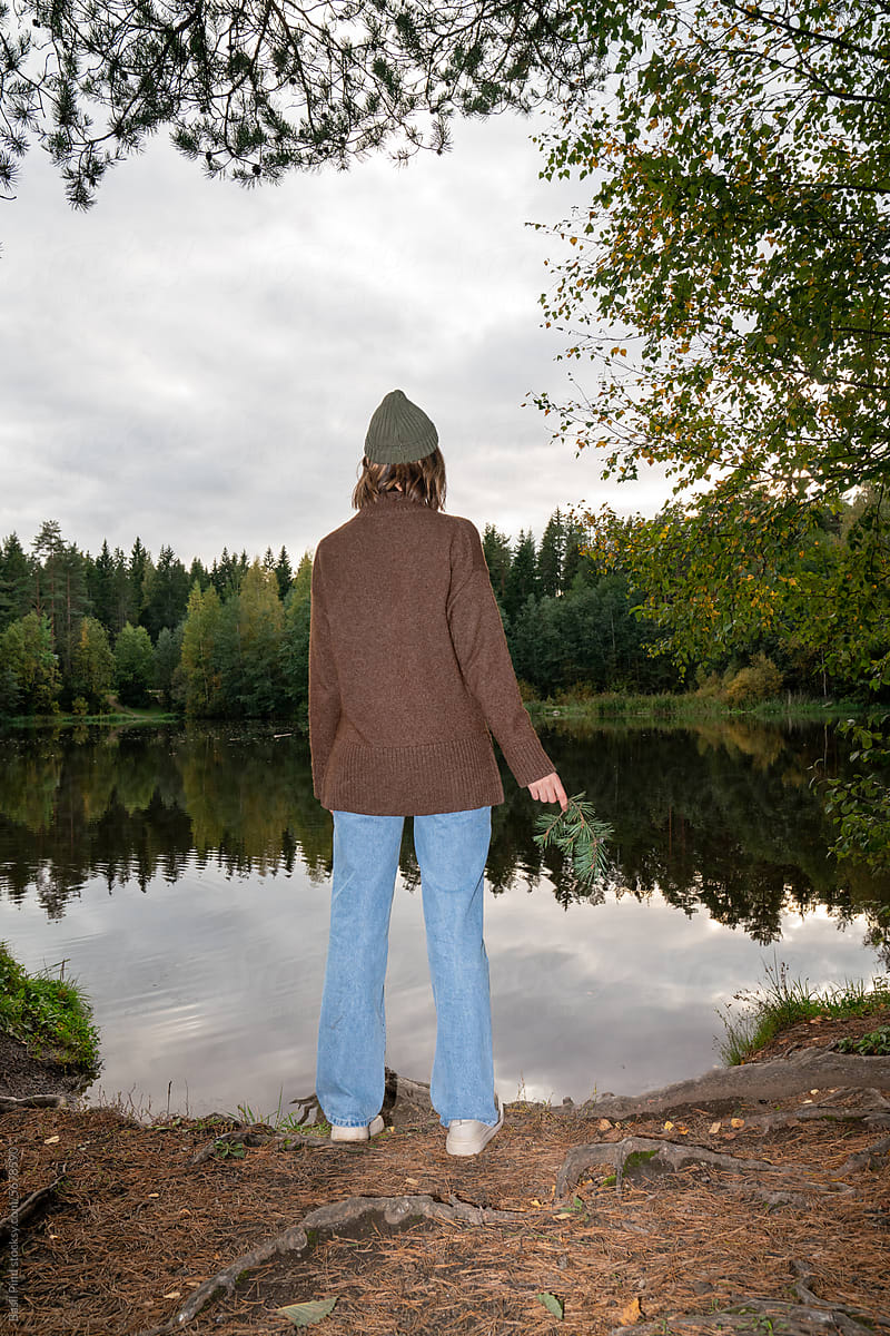 woman standing on the shore of a pond