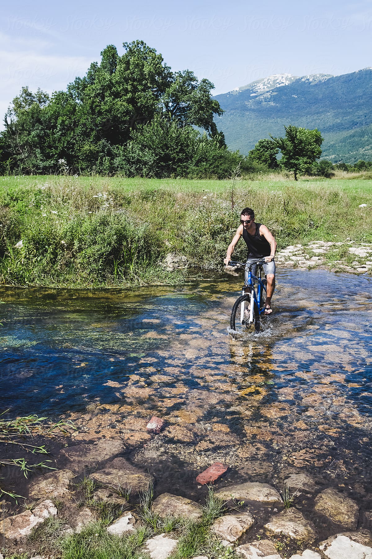 A Man crossing the river with a mountain bike