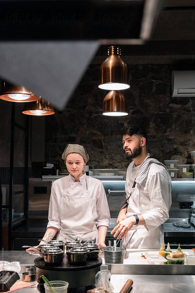 Man and woman behind table in restaurant kitchen