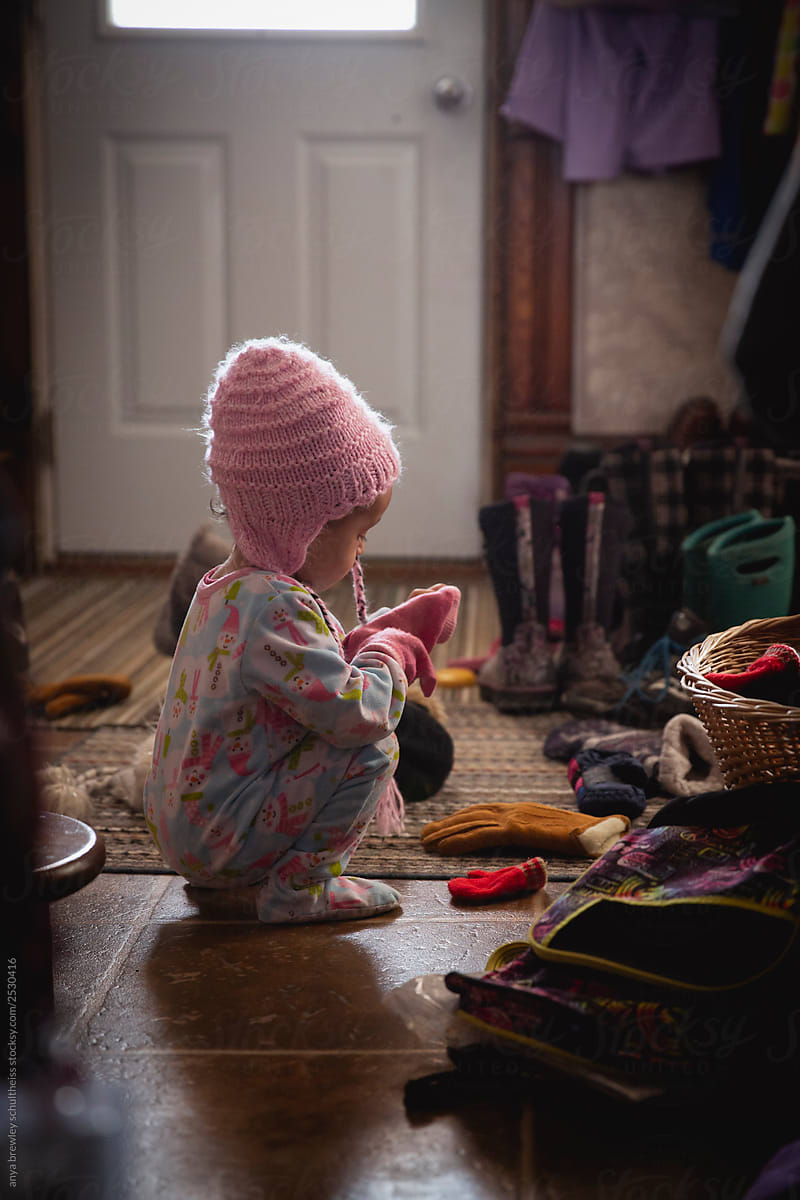 Toddler girl putting on winter mittens and a hat