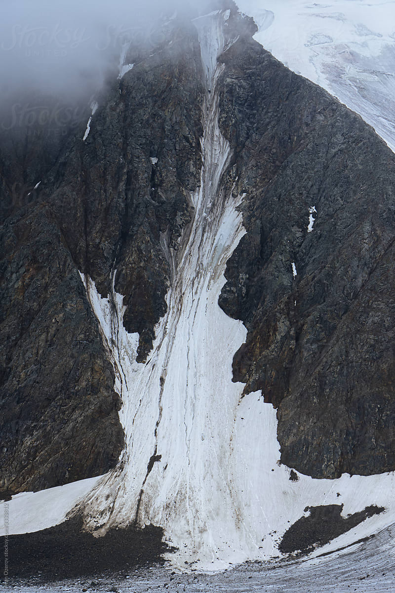 a huge snow mass lies on a vertical rock