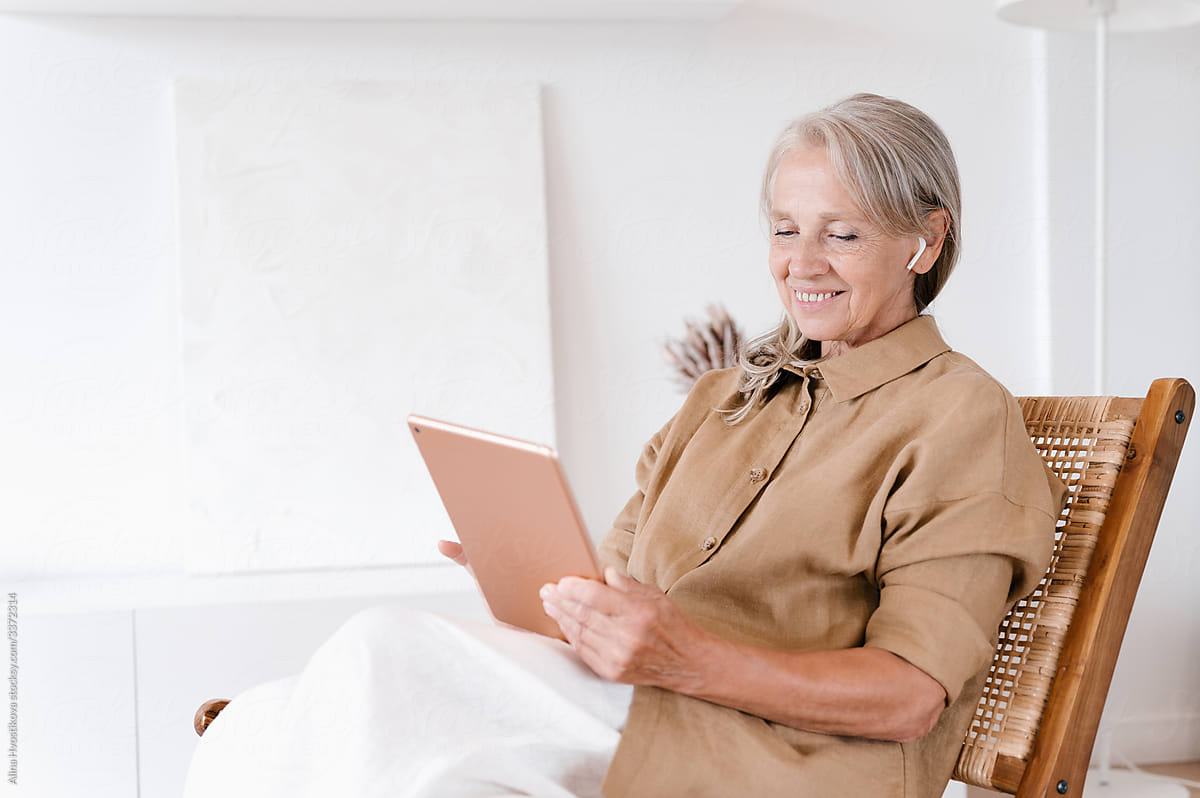 Happy senior woman using tablet on chair