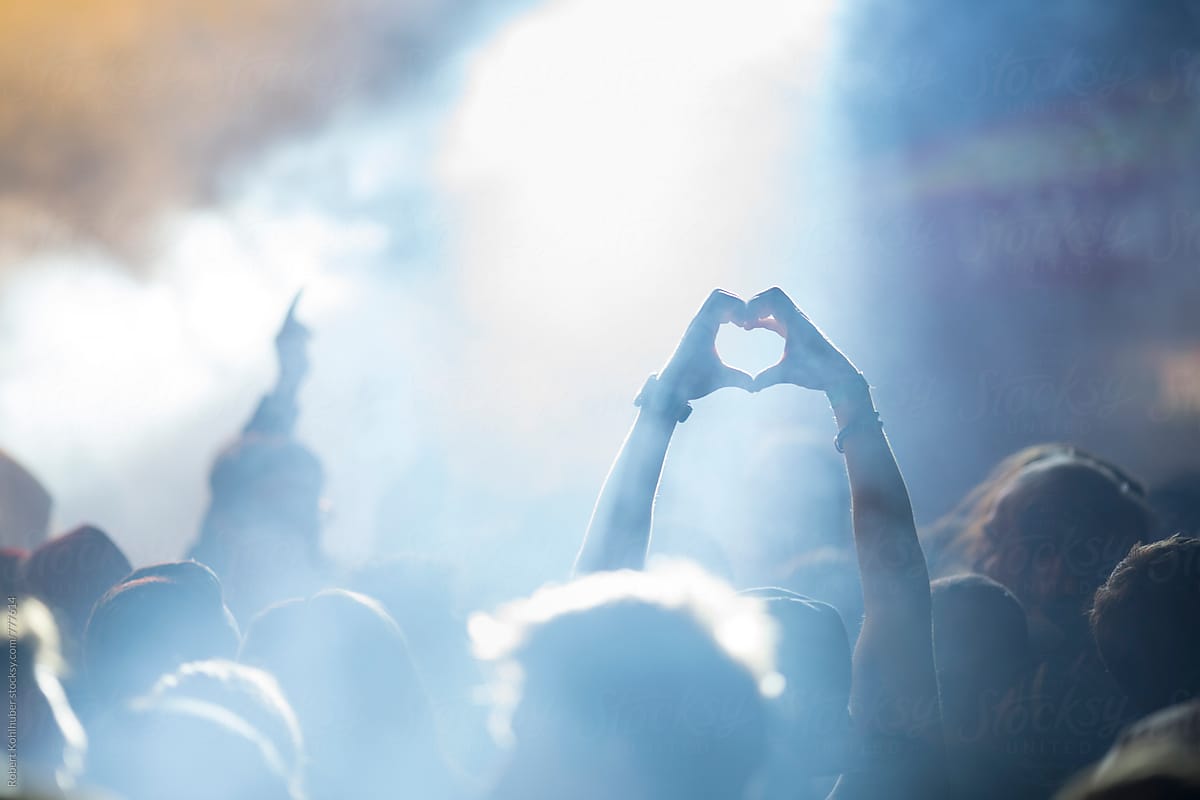 Fan forming heart with hands at live music concert, festival