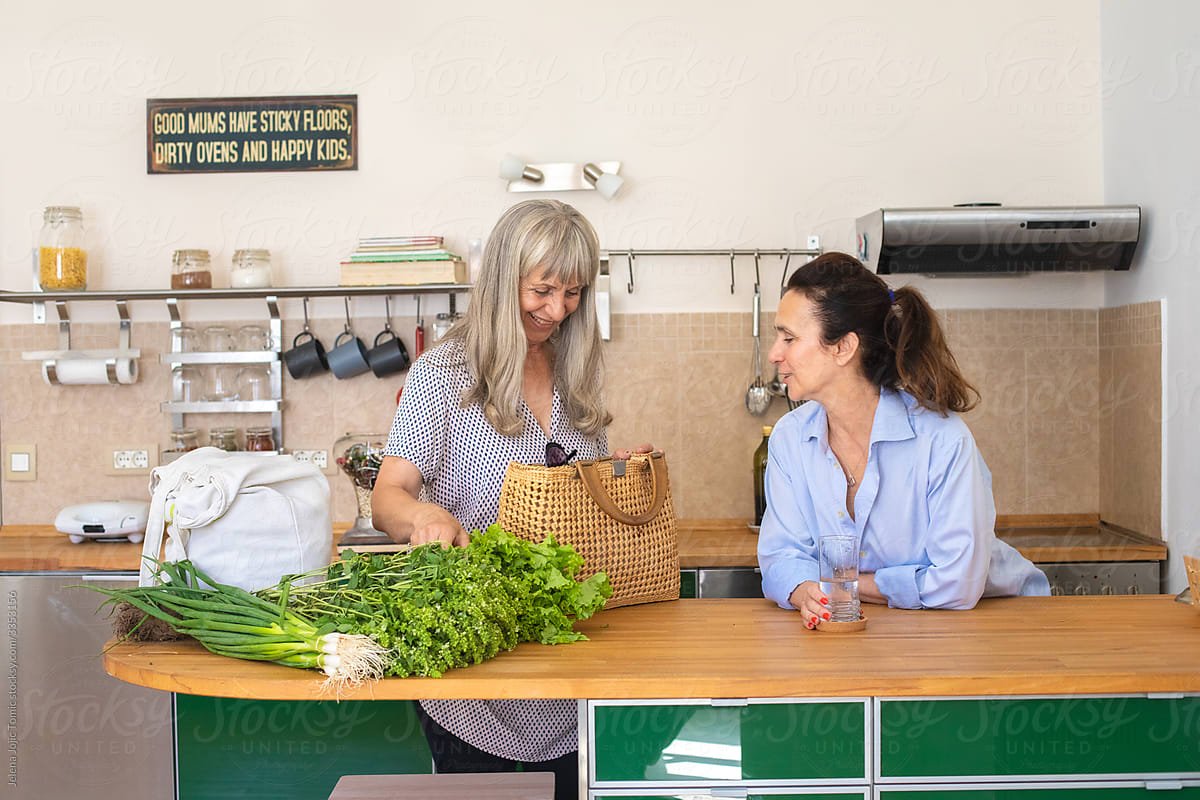Two elderly women at home unpack the fresh groceries from the market