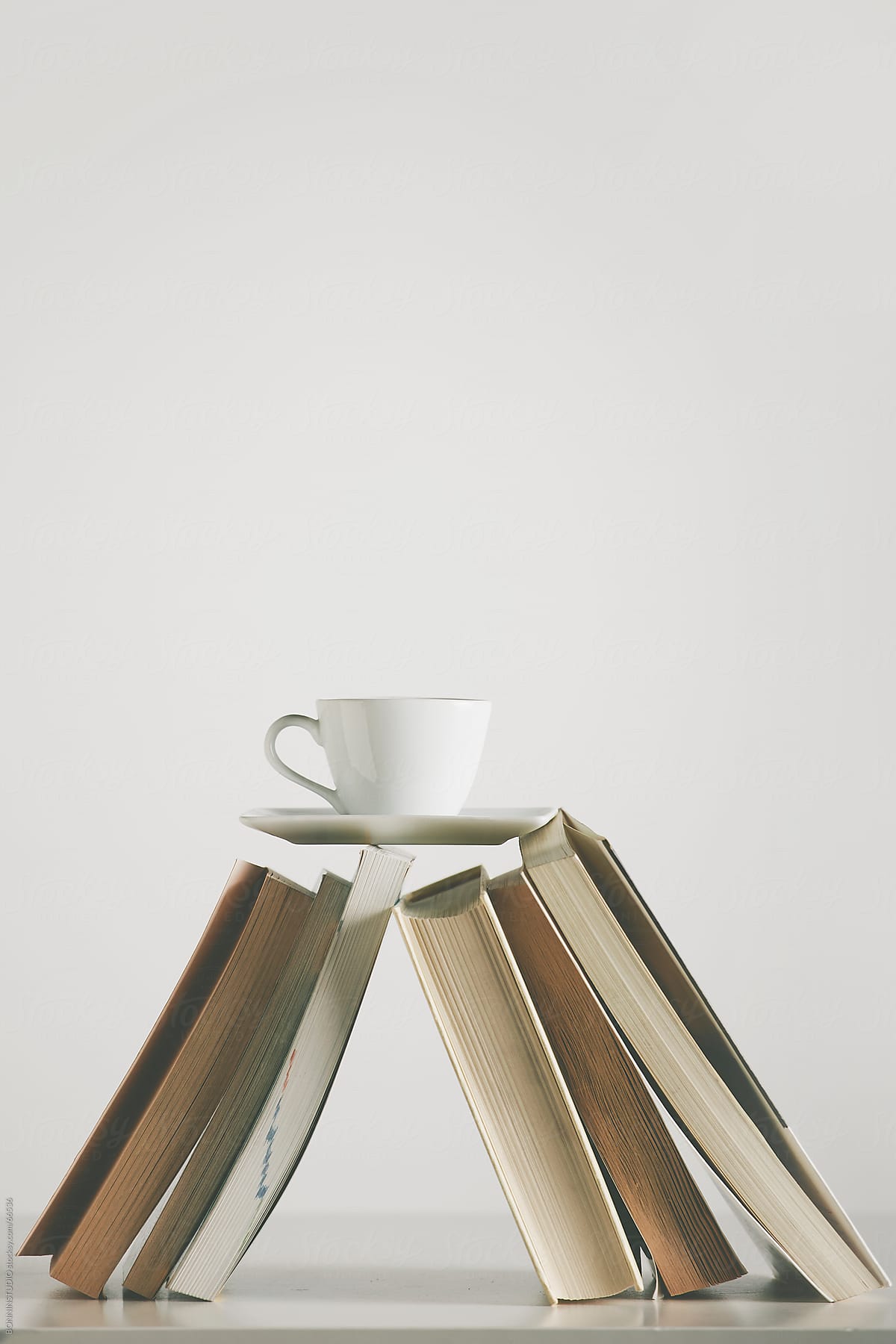 Coffee cup over a book on the table. White background.