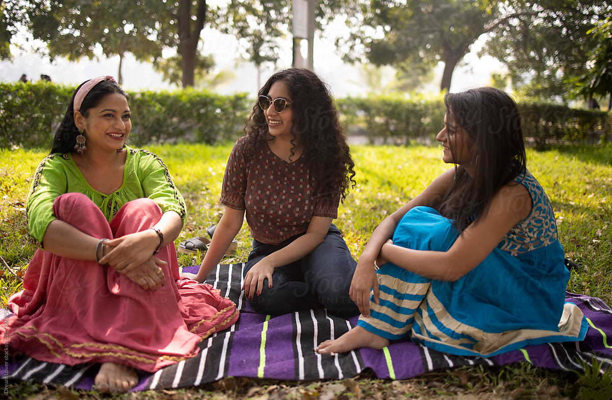 Three Indian girl sitting in a park and making conversation