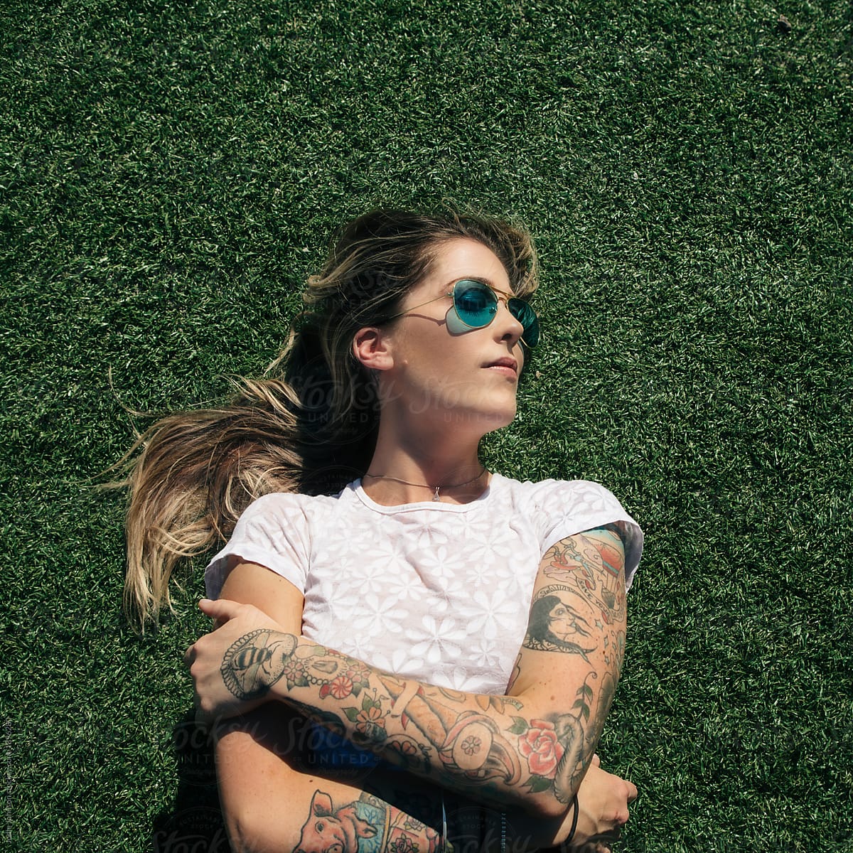 Blonde tattooed woman lying on the grass