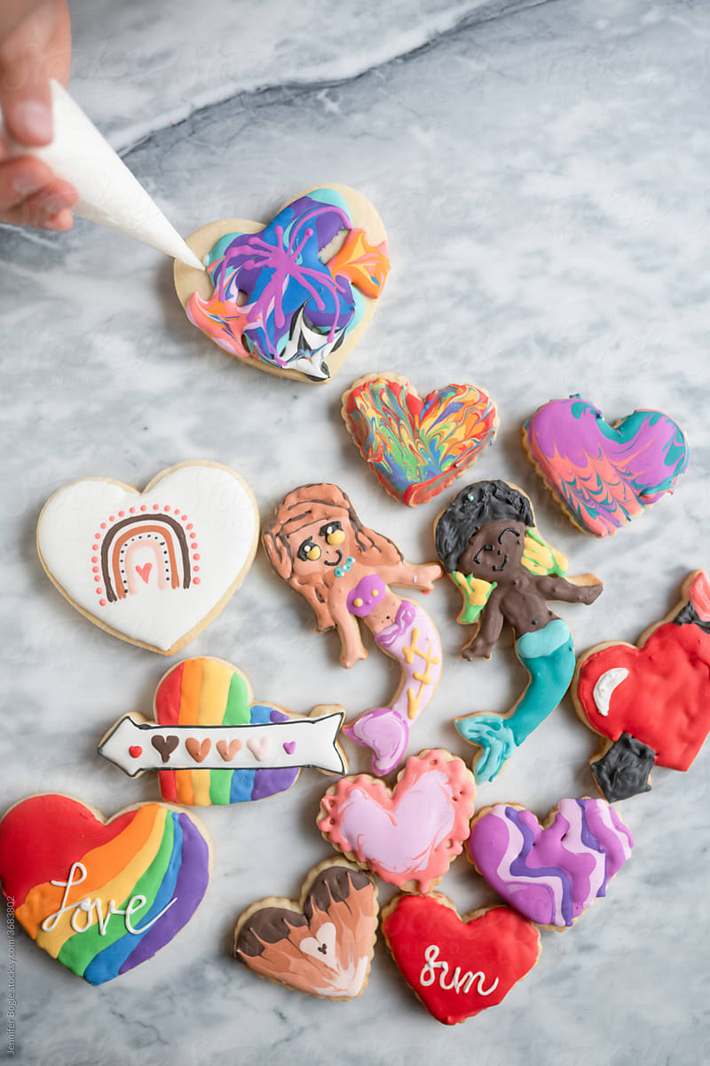 Child decorating diverse valentine cookies
