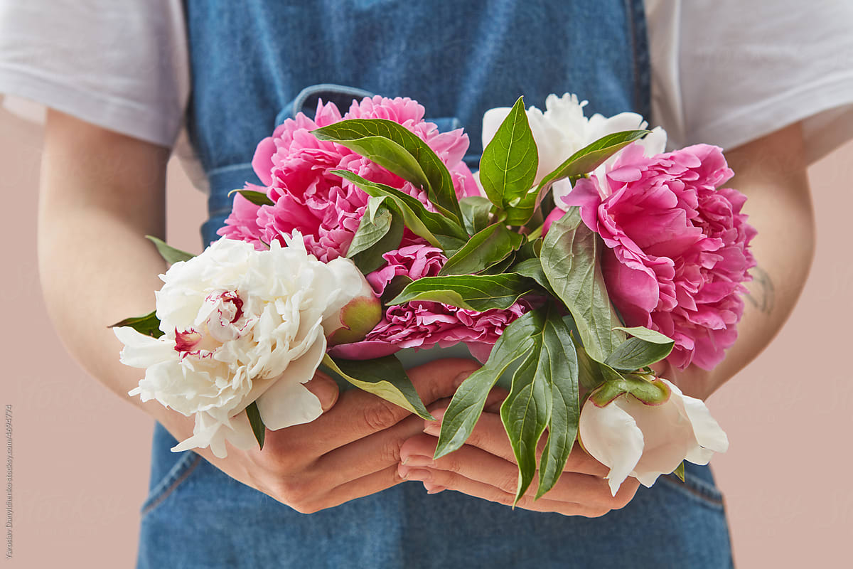 Girl holding pink and white peonies in hands.