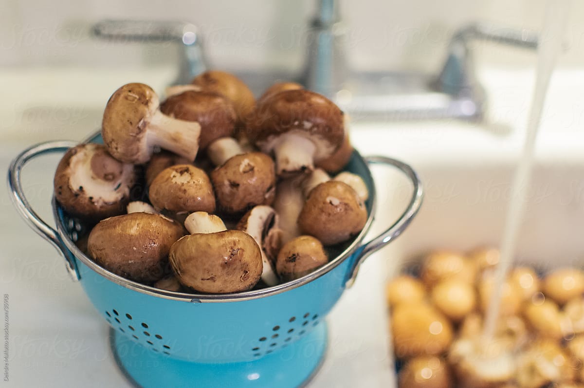 washed mushrooms in a colander next to a sink
