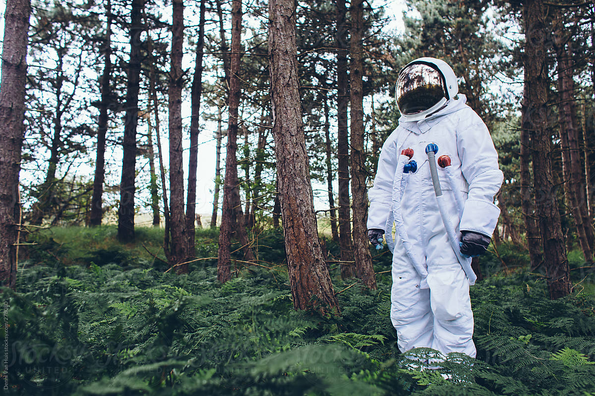 Man in space suit standing in a forest.