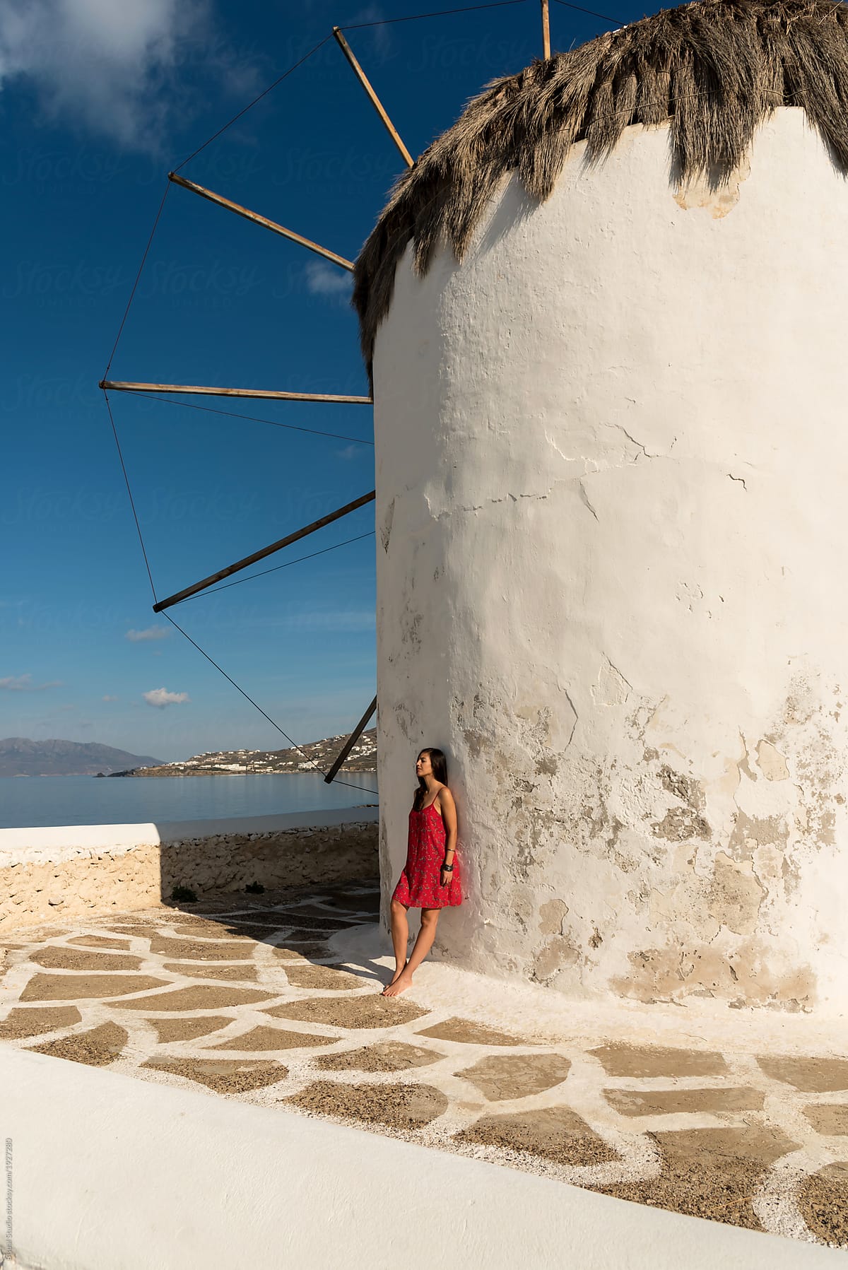 Woman leaning on white rough windmill in Mykonos