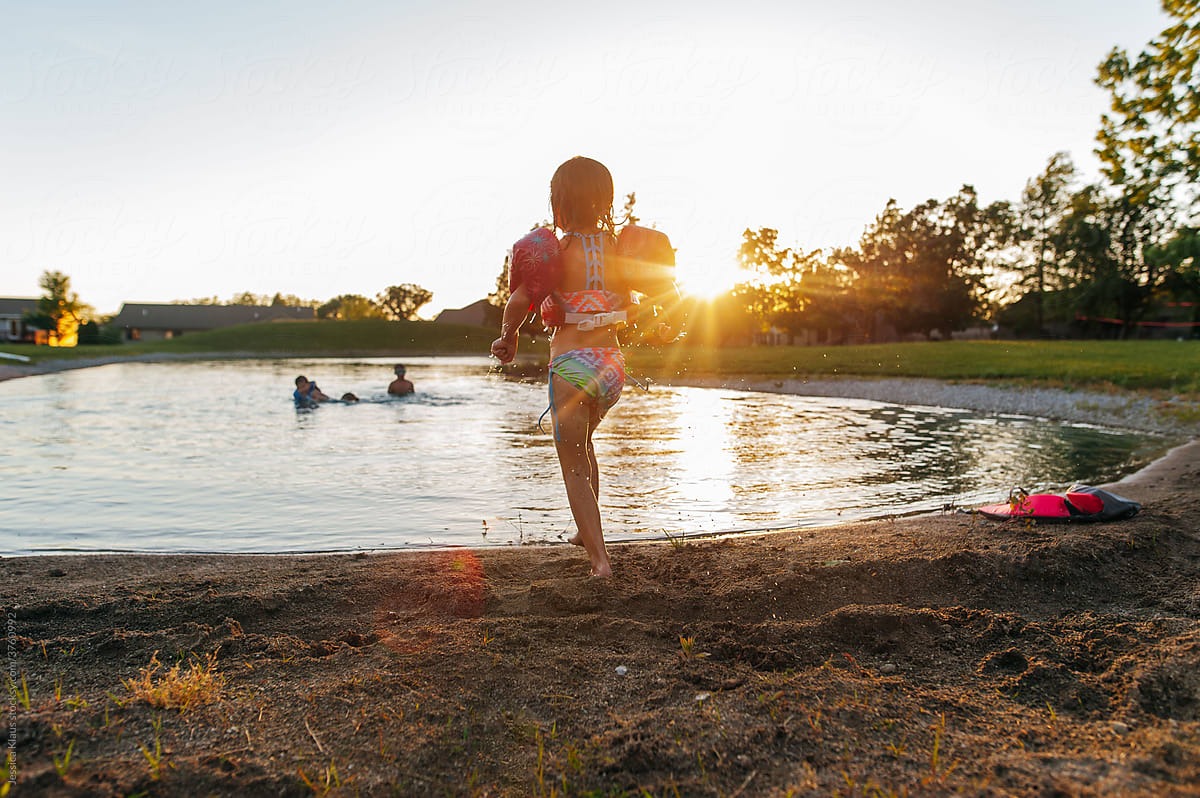 Children swimming in pond on a summer evening.