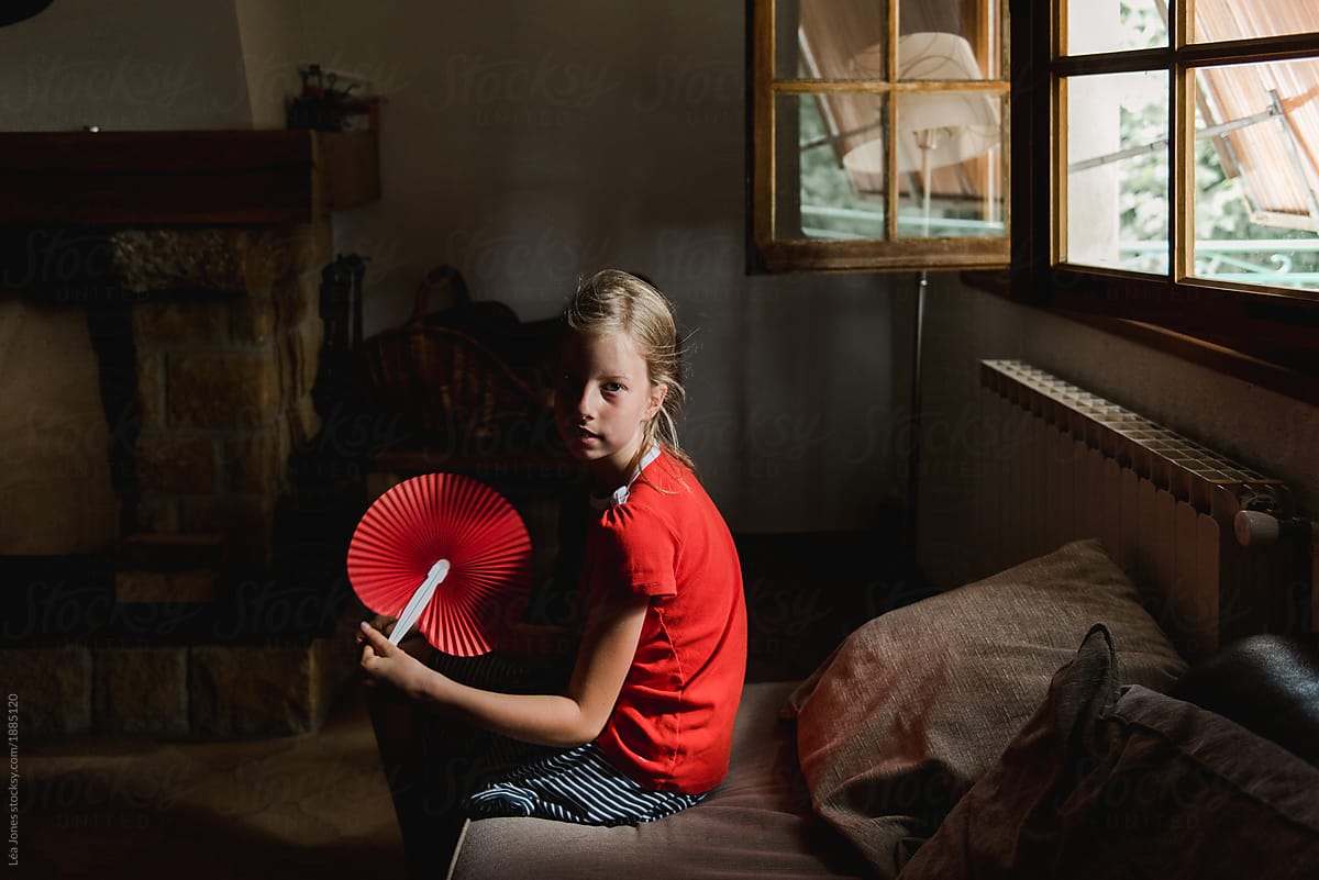 young girl with red shirt and red fan on a hot summer day