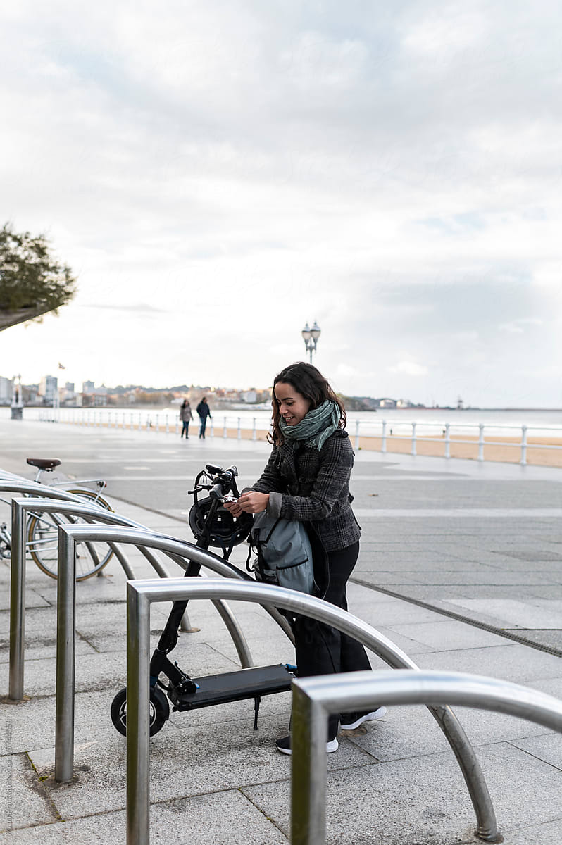 Woman parking e-scooter in city steet in wintertime