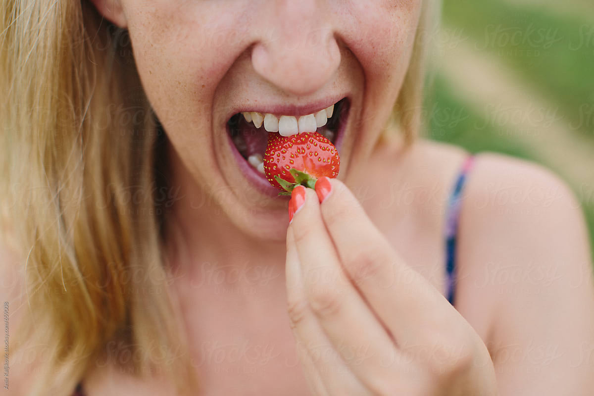 Woman biting into a succulent ripe strawberry
