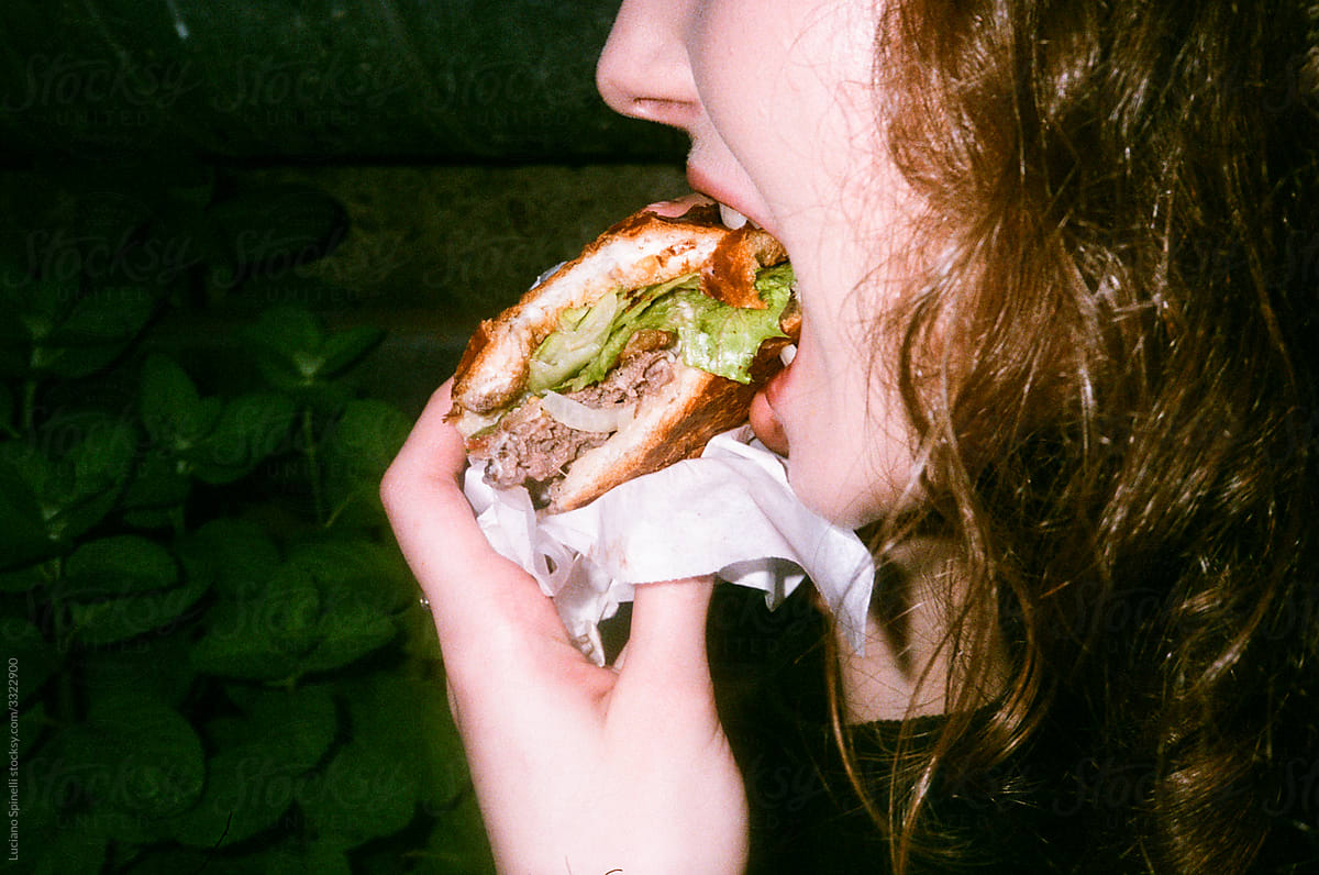 Anonymous girl / woman  eating a burger