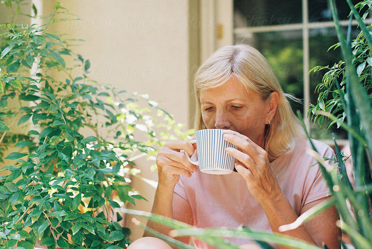 A senior woman with a cup of coffee in the garden