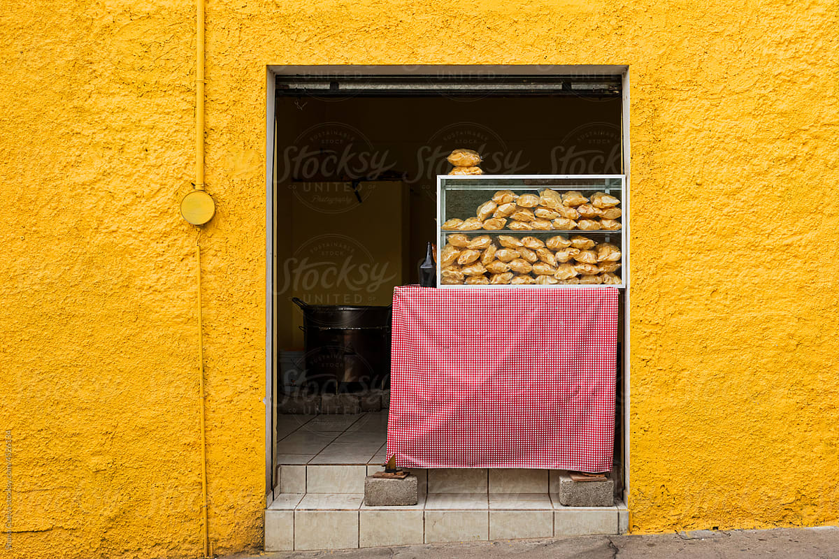 A yellow colored wall with a street food stall in the middle.