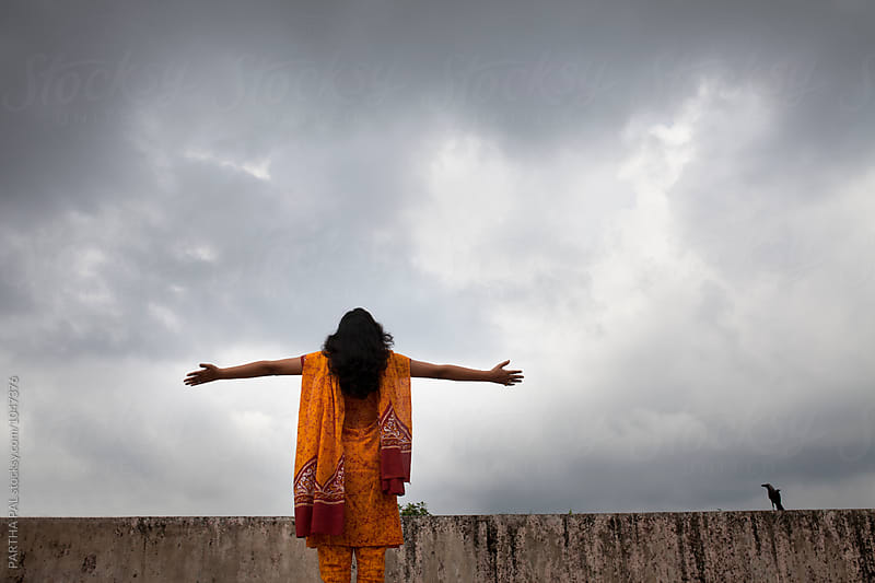 A young woman stretched arm and monsoon cloud at backdrop