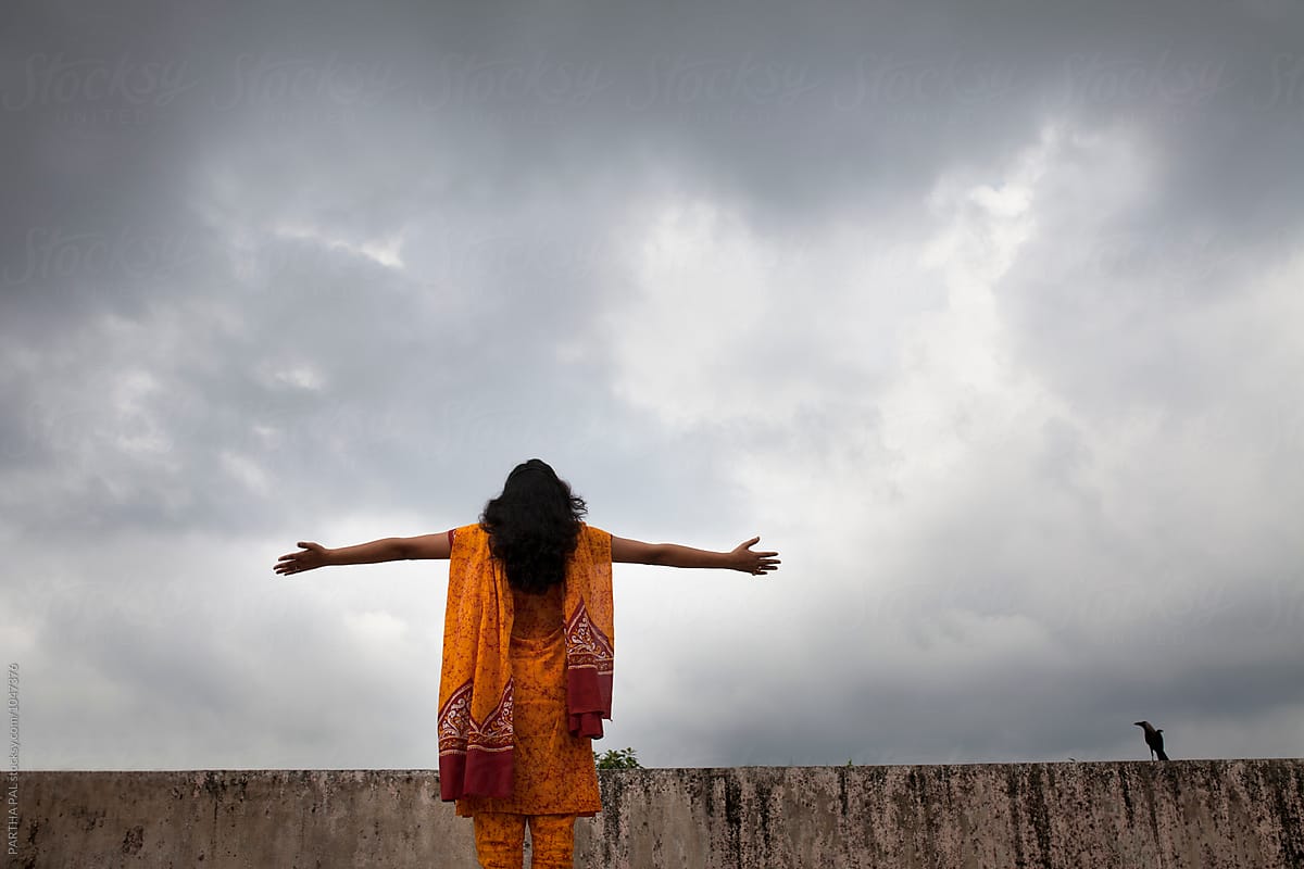 A young woman stretched arm and monsoon cloud at backdrop