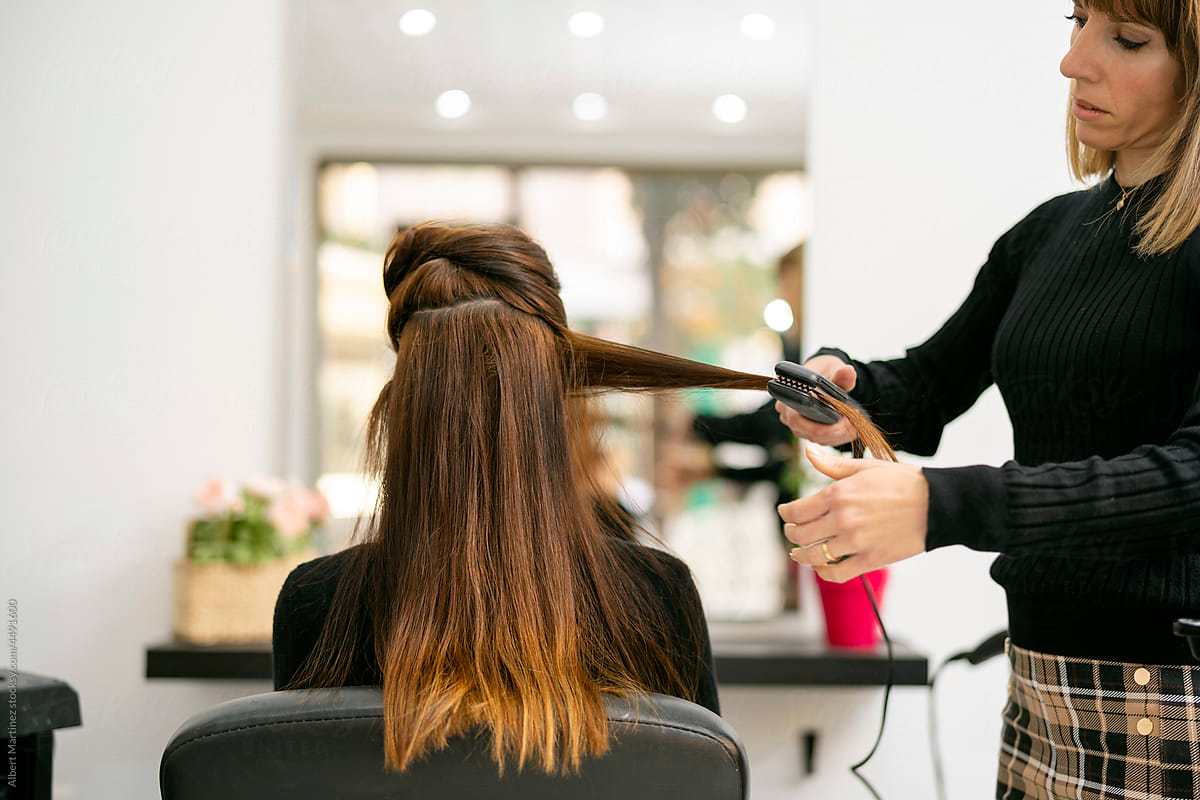 Hairdresser styling brown hair with hair straightener