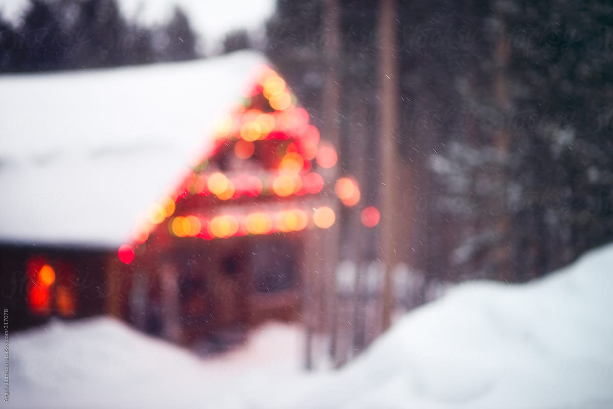 Holiday lights on a ski cabin surrounded by deep snow and pine trees