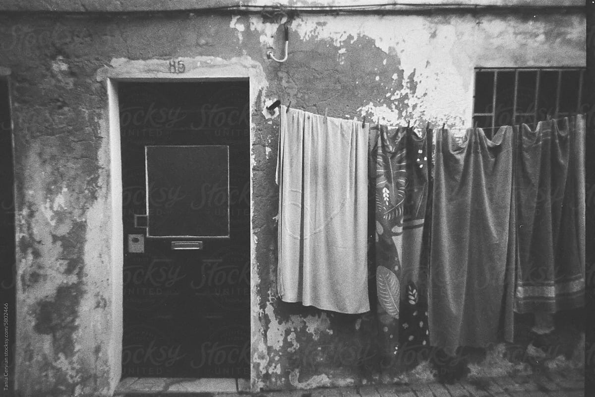 Film photography of old shabby house with clothes hanging on rope