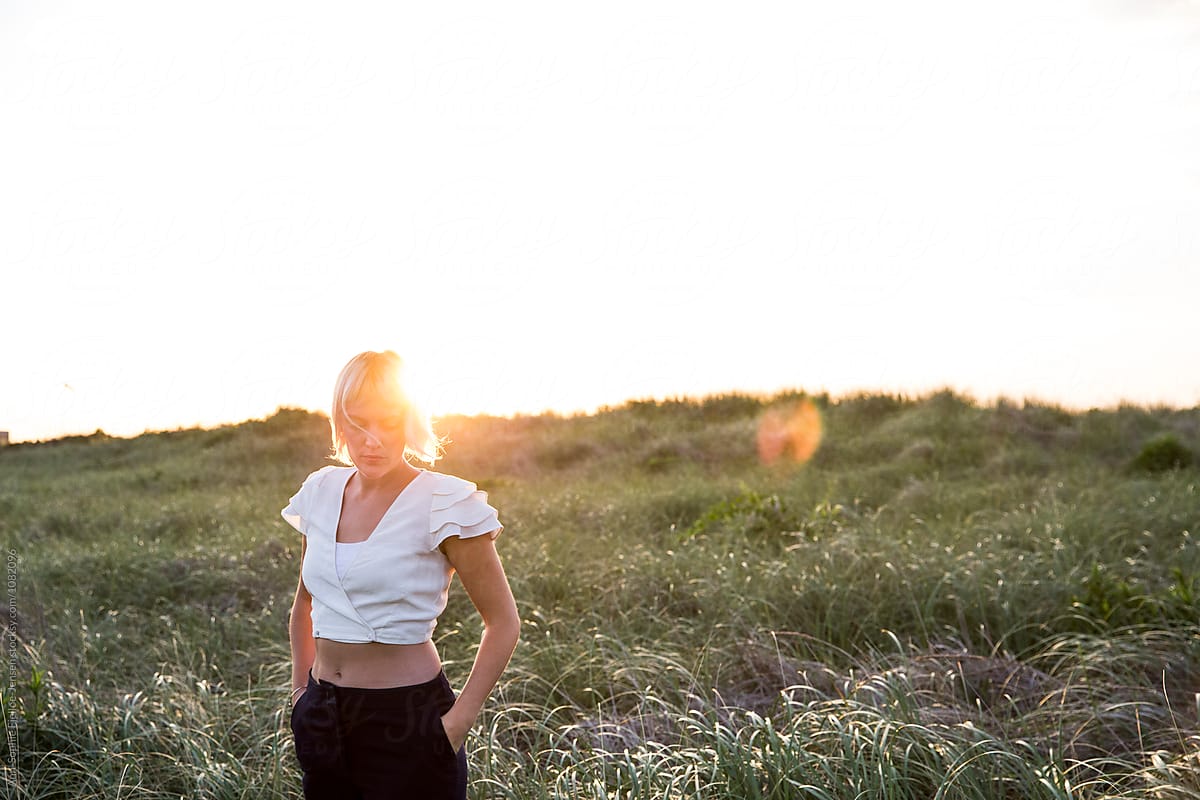 Woman standing in a field with the sun rising behind